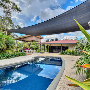 Design ideas for a large contemporary backyard custom-shaped pool in Darwin with natural stone pavers.