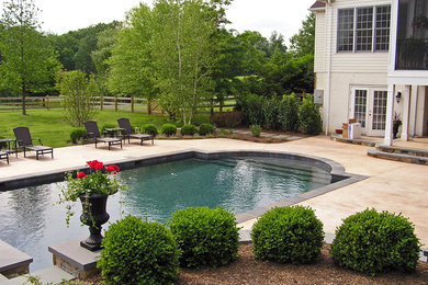 Ejemplo de piscina con fuente tradicional grande a medida en patio trasero con adoquines de piedra natural