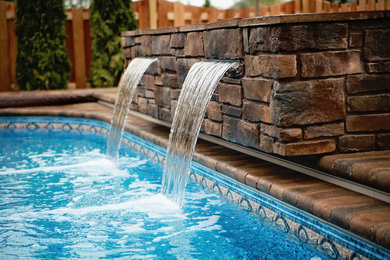 Diseño de piscina con fuente natural contemporánea grande a medida en patio trasero con adoquines de hormigón