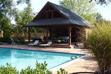 На фото: большой спортивный, прямоугольный бассейн на заднем дворе в стиле рустика с домиком у бассейна и покрытием из бетонных плит
