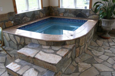 Ispirazione per una piscina coperta con una vasca idromassaggio e pavimentazioni in pietra naturale
