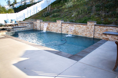 Foto de piscina tradicional de tamaño medio rectangular en patio trasero con losas de hormigón