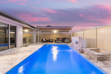 Ejemplo de piscina alargada minimalista rectangular en patio con adoquines de piedra natural