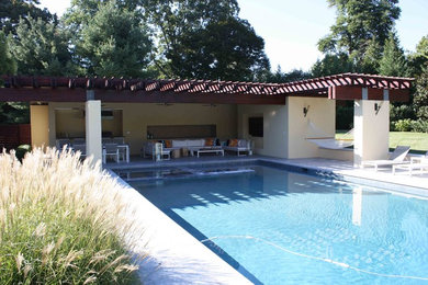 Ejemplo de casa de la piscina y piscina natural moderna grande rectangular en patio trasero con adoquines de piedra natural