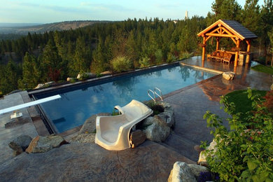 Foto di una piscina chic rettangolare di medie dimensioni e dietro casa con un acquascivolo e cemento stampato