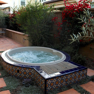 Modelo de piscinas y jacuzzis mediterráneos, de tamaño medio, redondeados, en patio trasero, con suelo de baldosas