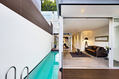 Imagen de piscina alargada contemporánea rectangular en patio lateral con entablado