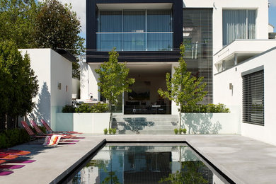 Ejemplo de piscina alargada contemporánea rectangular en patio trasero con losas de hormigón