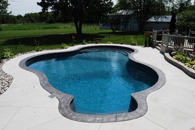 Foto de piscina tradicional grande a medida en patio trasero con losas de hormigón