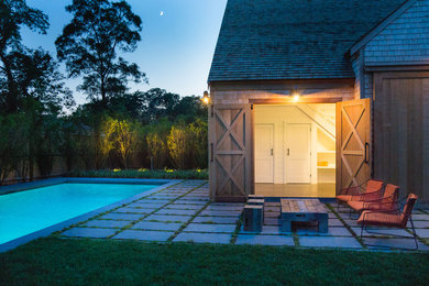 На фото: прямоугольный бассейн среднего размера на заднем дворе в стиле кантри с домиком у бассейна и покрытием из каменной брусчатки с
