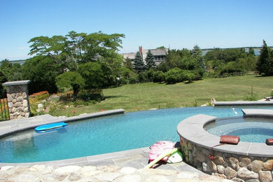 Diseño de piscinas y jacuzzis infinitos rurales grandes a medida en patio trasero con adoquines de piedra natural