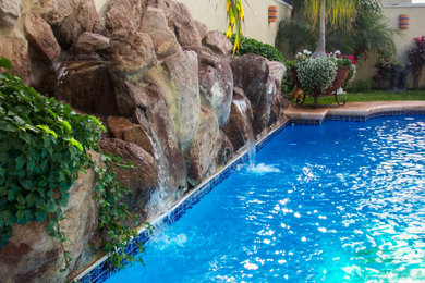 Diseño de piscina con fuente clásica de tamaño medio a medida en patio trasero