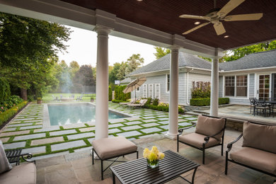 Diseño de piscina alargada rectangular en patio trasero con adoquines de piedra natural