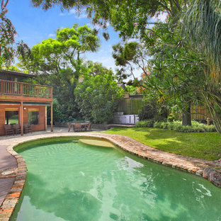 Photo of a large tropical backyard custom-shaped lap pool in Sydney with brick pavers.
