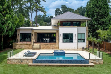 Diseño de piscinas y jacuzzis infinitos modernos de tamaño medio rectangulares en patio trasero con adoquines de piedra natural