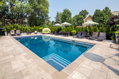 Imagen de piscina clásica de tamaño medio rectangular en patio trasero con adoquines de ladrillo