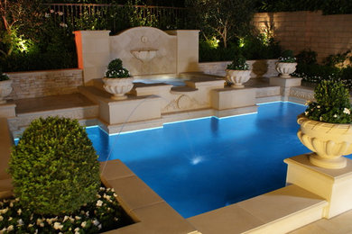 Ejemplo de piscina con fuente mediterránea pequeña a medida en patio trasero con adoquines de hormigón
