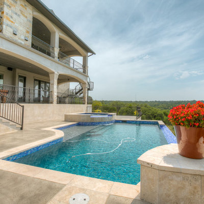 Large tuscan backyard concrete and rectangular infinity hot tub photo in Austin