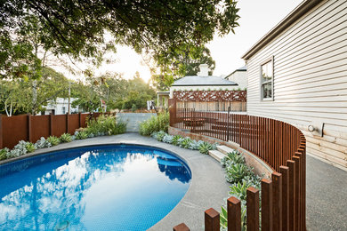 Diseño de piscina minimalista de tamaño medio redondeada en patio lateral