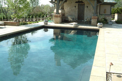Modelo de piscina con fuente natural clásica grande rectangular en patio trasero con suelo de hormigón estampado
