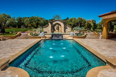 Modelo de piscina con fuente mediterránea a medida en patio trasero