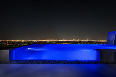 Example of a small minimalist backyard tile and rectangular infinity pool design in Las Vegas