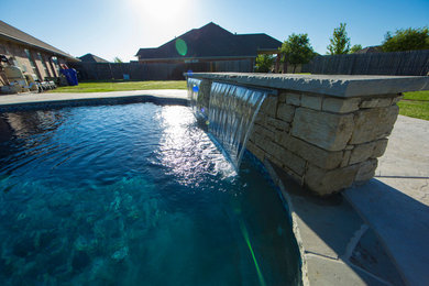 Modelo de piscina con fuente natural mediterránea grande a medida en patio trasero con suelo de hormigón estampado