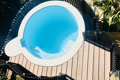 Modelo de piscina elevada actual pequeña redondeada en patio trasero con entablado