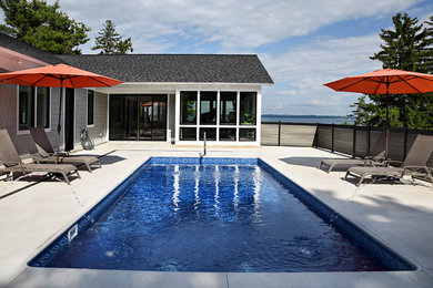 Ejemplo de piscina con fuente marinera rectangular en patio trasero con losas de hormigón