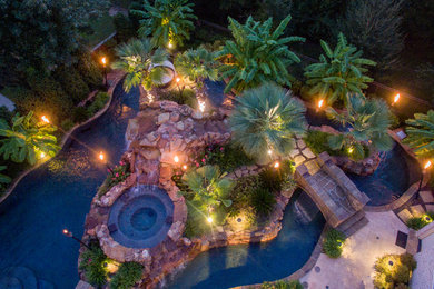 Pool fountain - large tropical backyard stone and custom-shaped pool fountain idea in Dallas