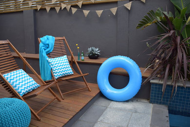Diseño de piscina con fuente tropical grande rectangular en patio trasero con adoquines de piedra natural