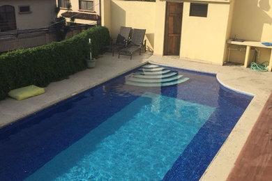 Immagine di una piscina fuori terra rettangolare di medie dimensioni e dietro casa con lastre di cemento
