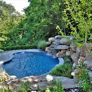 Small country backyard kidney-shaped natural pool in New York with a water feature and natural stone pavers.