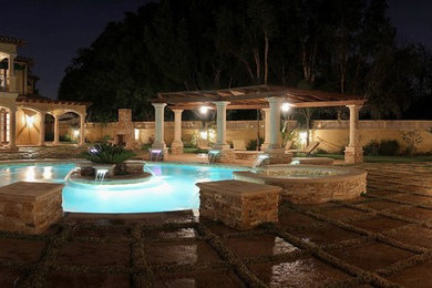 Inspiration for a large mediterranean backyard stone and custom-shaped pool house remodel in Los Angeles