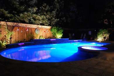 Foto de piscina con fuente natural minimalista de tamaño medio a medida en patio trasero con adoquines de hormigón
