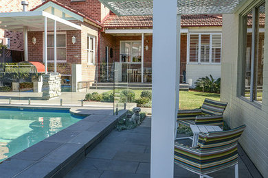 Ejemplo de piscina con fuente alargada actual de tamaño medio rectangular en patio trasero con adoquines de hormigón
