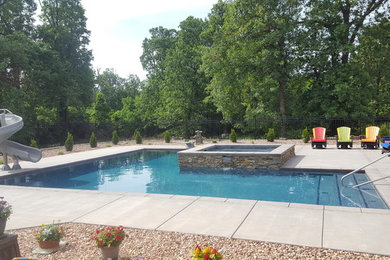 Ejemplo de piscina clásica extra grande en forma de L en patio trasero con losas de hormigón