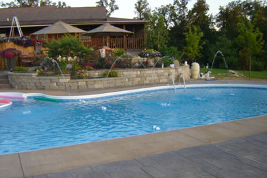 Foto de piscina con fuente grande a medida en patio trasero con adoquines de hormigón
