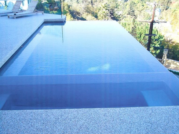 A small contemporary backyard with a rectangular infinity hot tub is an example.