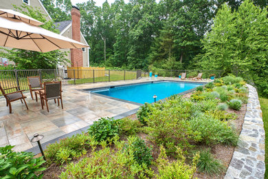 Example of a mid-sized classic side yard stone and rectangular infinity pool landscaping design in Boston