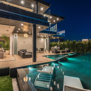 Foto di una grande piscina a sfioro infinito minimal rettangolare dietro casa con una vasca idromassaggio e pedane