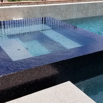 Contemporary pool and jacuzzi with black glass mosaic tile