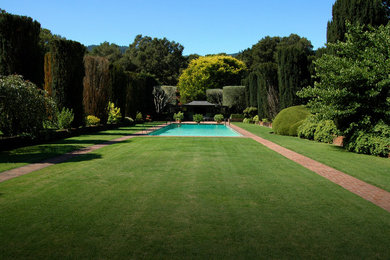 Ejemplo de piscina contemporánea grande rectangular en patio trasero con adoquines de ladrillo