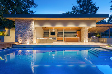 Foto de casa de la piscina y piscina actual grande rectangular en patio trasero con suelo de baldosas