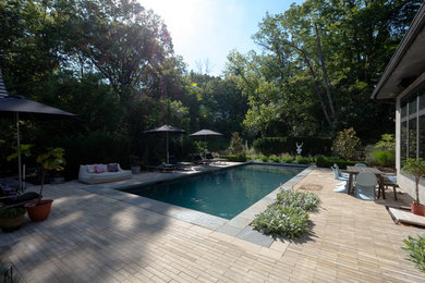 Ispirazione per una piscina contemporanea rettangolare di medie dimensioni e dietro casa con pavimentazioni in cemento