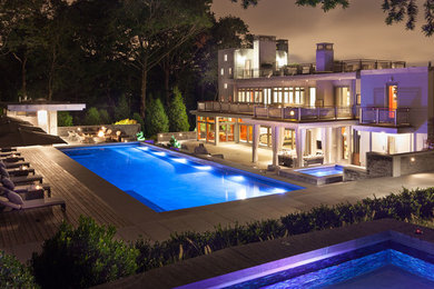 Diseño de piscina con fuente infinita actual grande rectangular en patio trasero con adoquines de hormigón