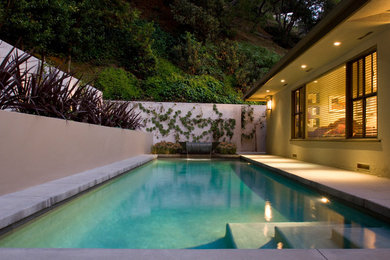 Imagen de piscina contemporánea de tamaño medio rectangular en patio trasero con losas de hormigón