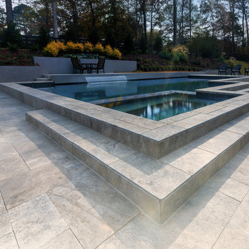 Contemporary style pool with silver travertine deck and custom water feature