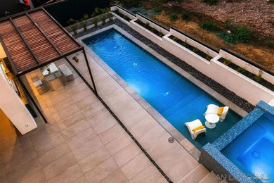 Imagen de piscina con fuente alargada actual grande rectangular en patio trasero con losas de hormigón
