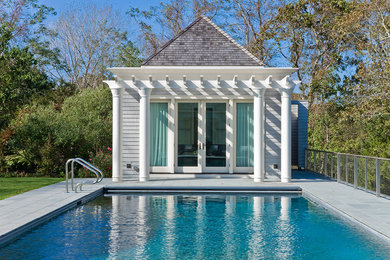 Exempel på en mellanstor klassisk rektangulär pool, med poolhus och marksten i betong